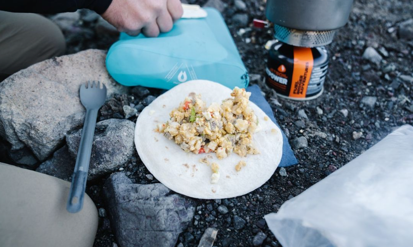 camping stove with tortilla meal and fork on the ground